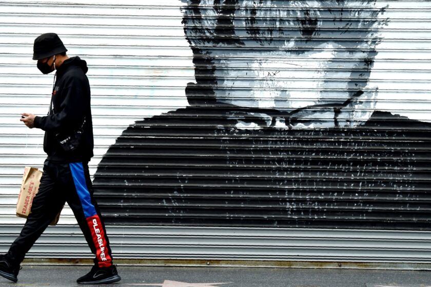 A shopper walks past a storefront mural depicting actor James Dean in Los Angeles on Tuesday.