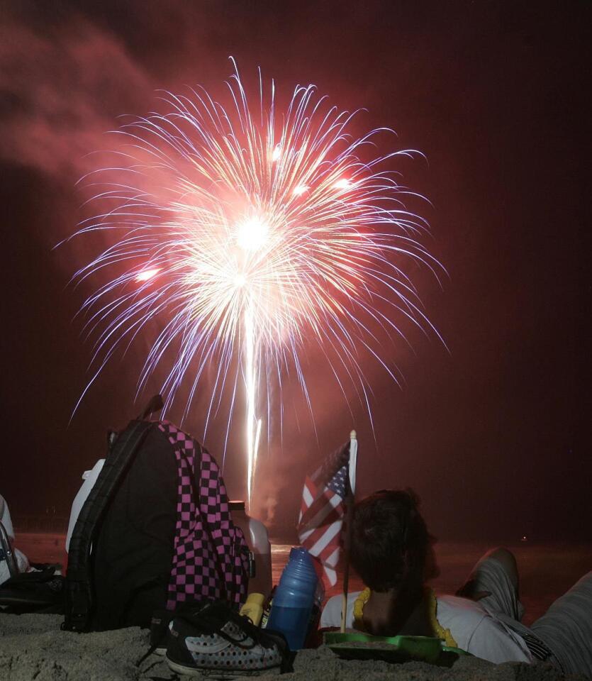 Onlookers watch fireworks go off from the Huntington Beach Pier on the Fourth of July.