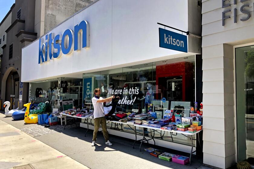 LOS ANGELES, CALIF. - MAY 11, 2020 - Kitson employee Tom Ernst rearranges merchandise displayed to attract walk-by customers on Robertson Boulevard in Los Angeles. While some employees around the U.S. have been squeamish about returning to face to face retail work, Ernst is thrilled to feel needed again and have a place to go outside his home. "It's been so great to be back to work," he said. (Ronald D. White / Los Angeles Times)
