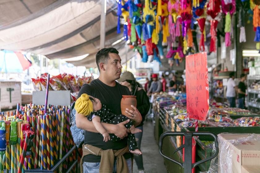 LOS ANGELES, CALIFORNIA - MAR. 24, 2019: Francisco Martinez carries his 4-months-old daughter Andrea as he and his family shop at the Navarros Party Supply store, which caries produce, party supples and house-wares, at the Pi–ata District street-food market on Sunday morning, Mar. 24. 2019, in Downtown Los Angeles. The food market grew organically around the existing produce, party-supplies, and household market over the course of last couple of decades. (Photo / Silvia Razgova) 3075323_la-me-street-food-tour