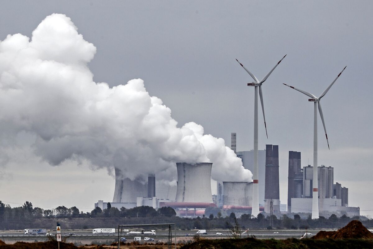 FILE - In this Sept.25, 2020 file photo a coal fired power station steams near the Garzweiler surface coal mine in Germany. Germany's environment minister said Wednesday that the government is considering additional spending to meet the new climate targets it has set for the coming decade. (AP Photo/Martin Meissner, file)