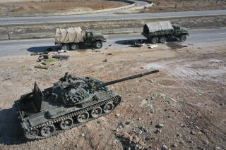 Abandoned military vehicles by a road.
