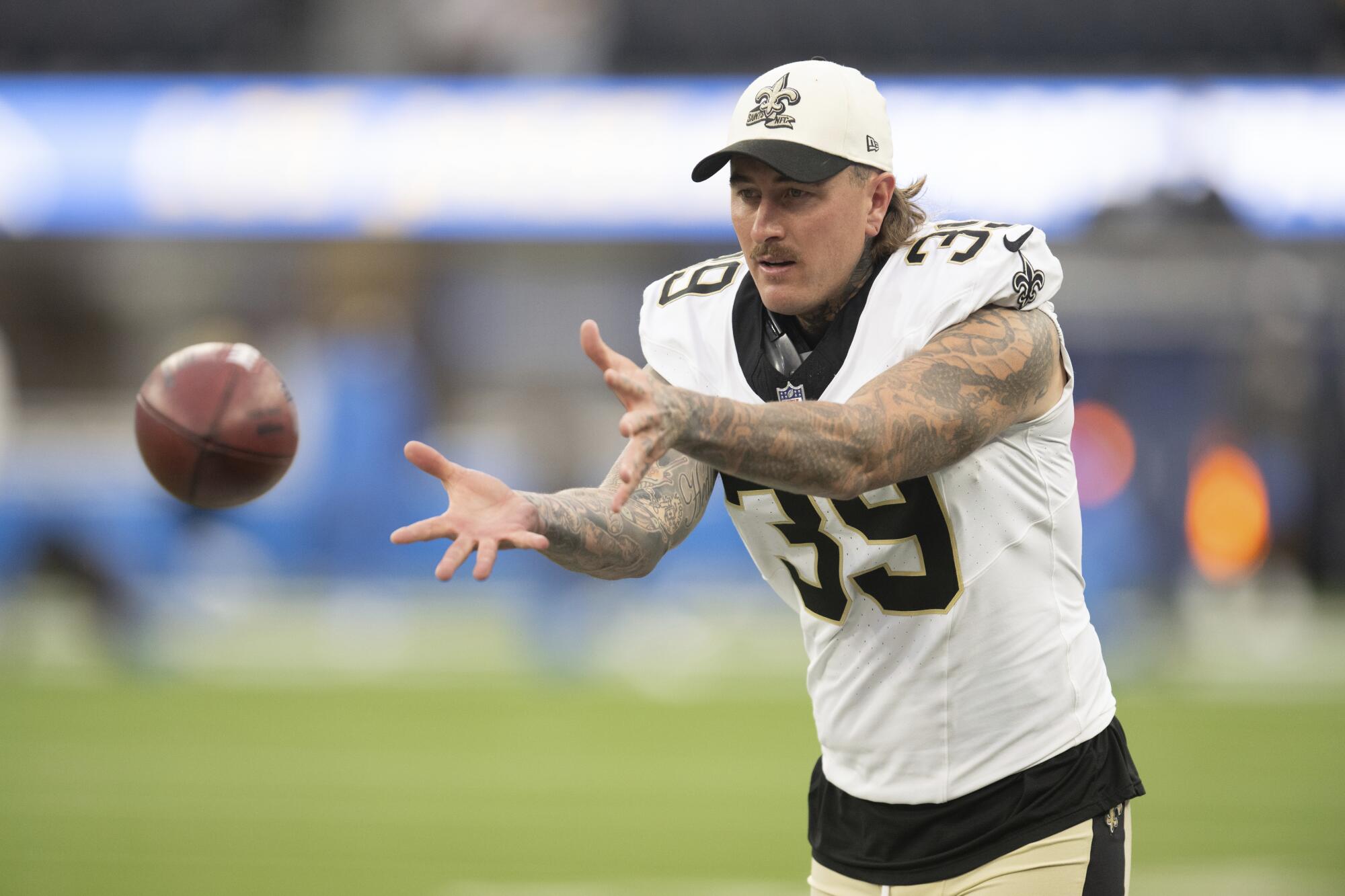 Saints punter Lou Hedley extends his hands to catch a football, warming up before a preseason game against the Chargers