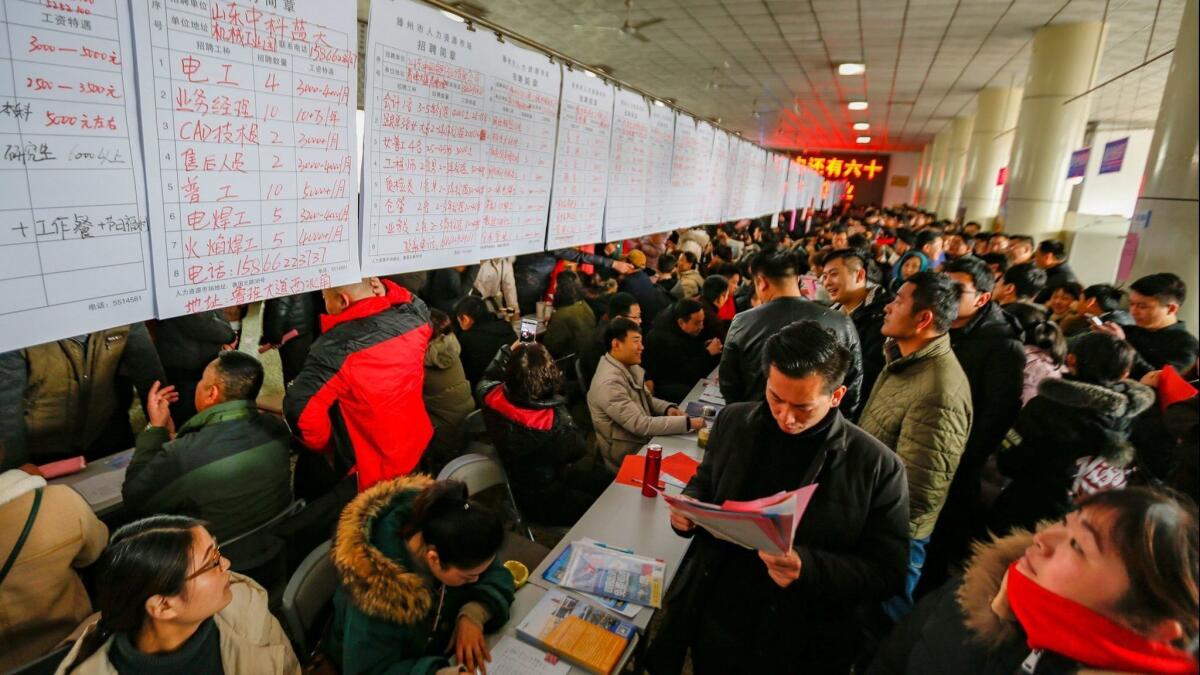 Chinese workers scan listings at a job fair in Tengzhou, eastern China, as factories struggle to find young workers.