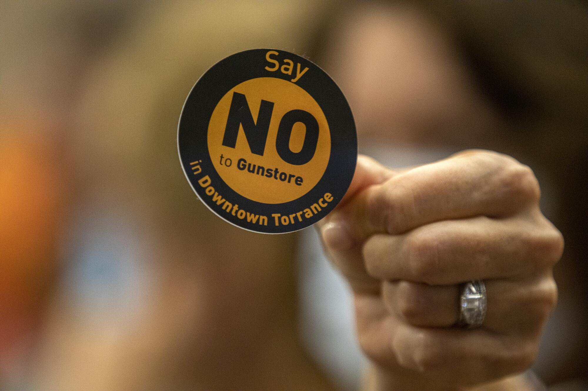 A member of the public holds up a sticker during a Torrance planning commission meeting.