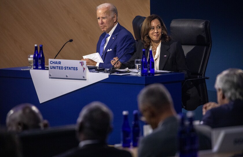 President Biden and Vice President Kamala Harris sit at a table before an audience