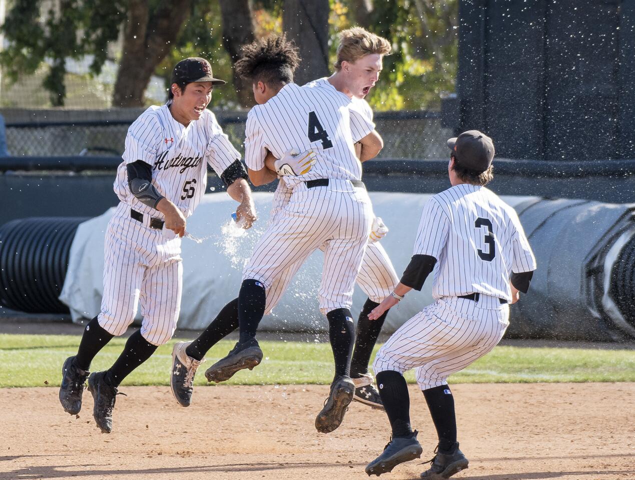 Jag Burden, center, is mobbed by Huntington Beach High teammates Ken Takada (56), Edward Pelc (4) and Brady Malpass (3) after his walk-off hit lifted the Oilers to a 2-1 win over La Puente Bishop Amat in the second round of the CIF Southern Section Division 1 playoffs at home on Tuesday.