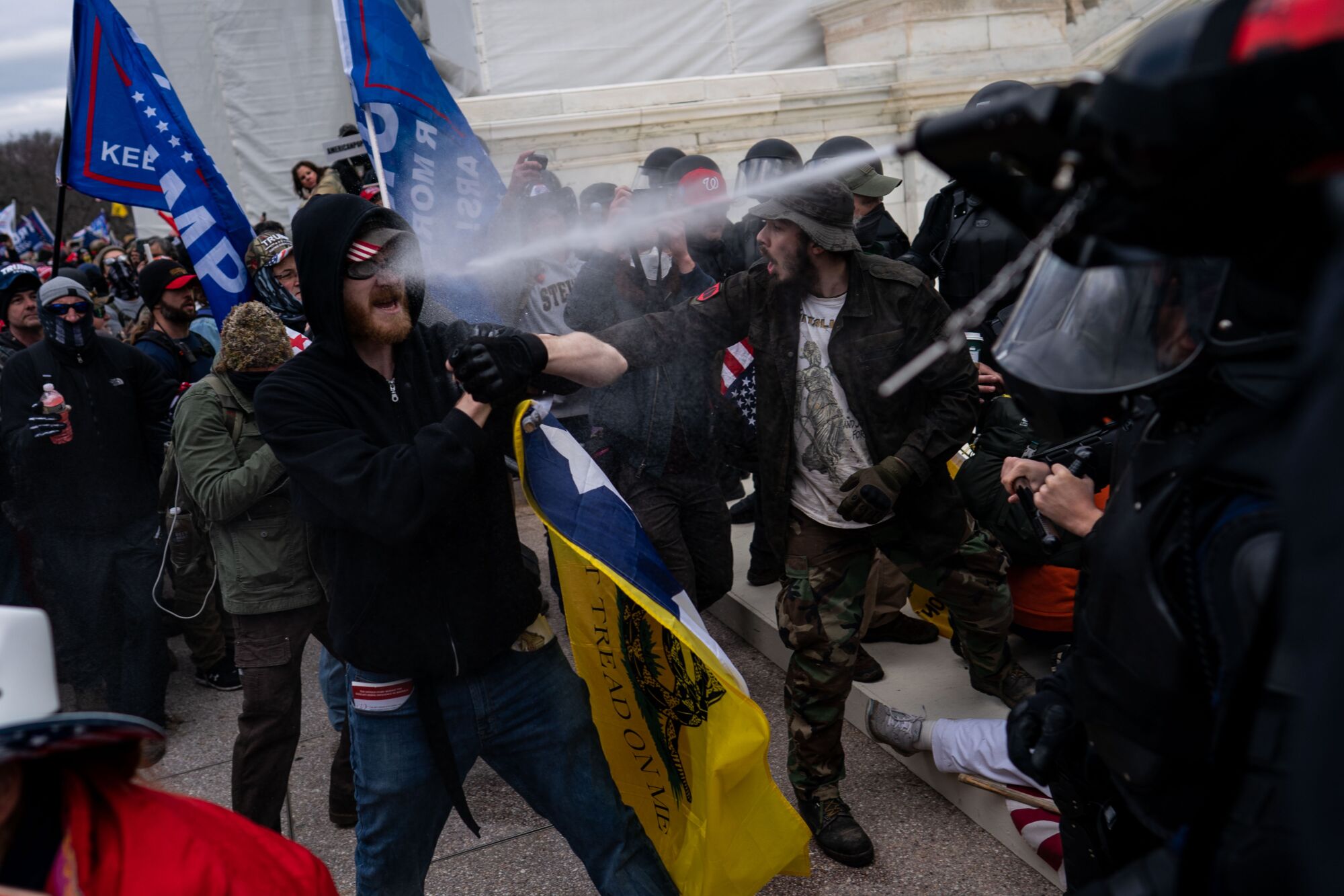 A man is sprayed in the face as protesters clash with police