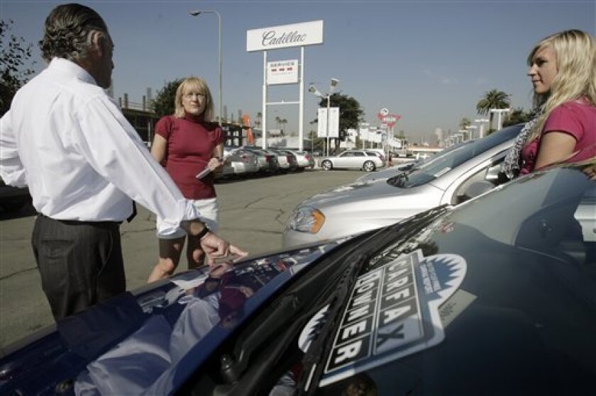 Chevrolet salesman Philip Jordan, left, assists Charlotte Olson, center, who's looking to buy a car for her 18-year-old daughter, Kari Olson, right, Wednesday, Nov. 12, 2008, in downtown Los Angeles. Treasury Secretary Henry Paulson called autos a "critical industry" Wednesday but said a $700 billion financial rescue program wasn't designed for them. The White House was noncommittal, but said it was open to new ideas. (AP Photo/Ric Francis)