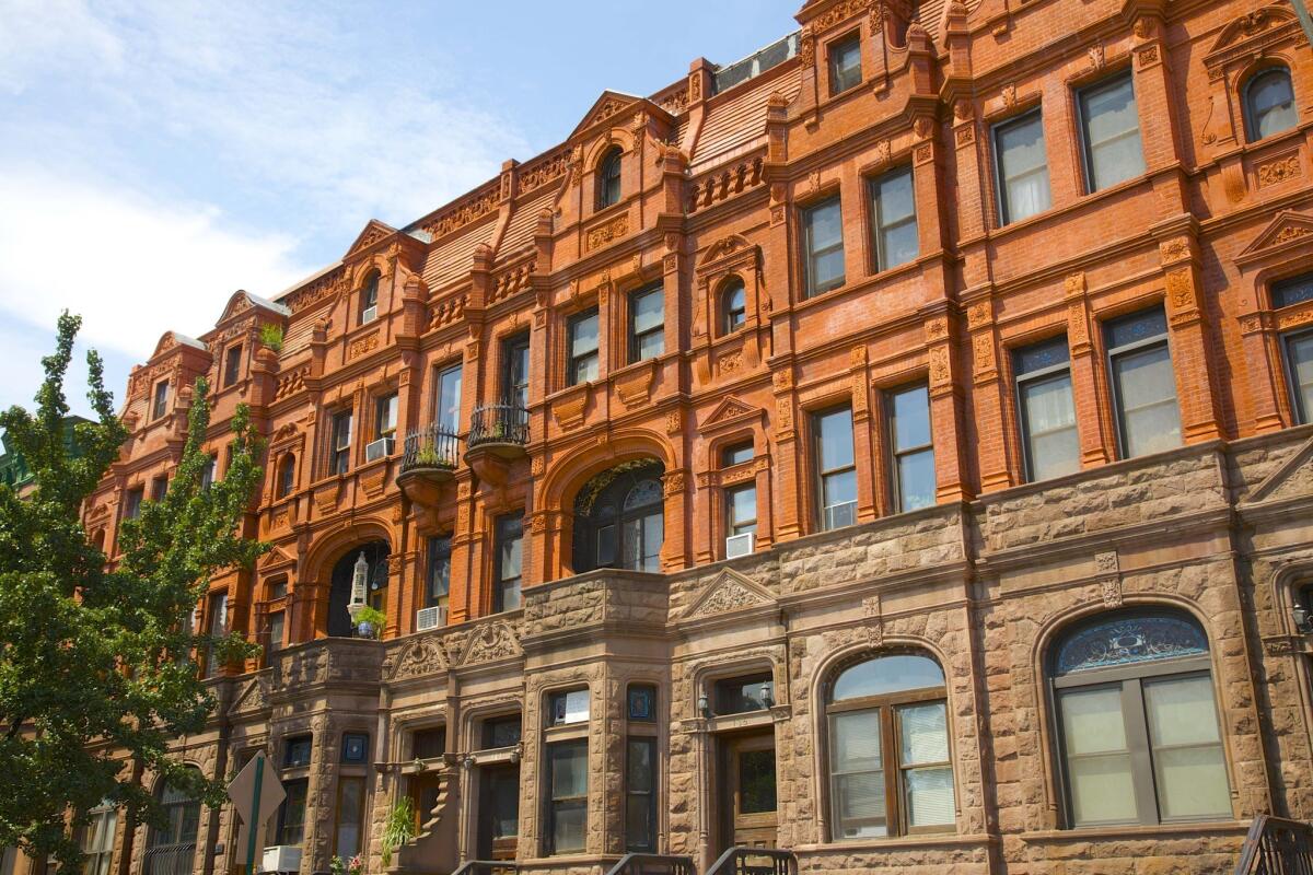 Red and brown brownstones line a street in Harlem.