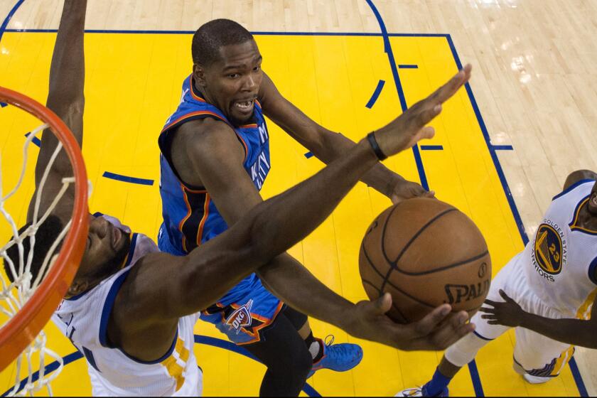 Thunder forward Kevin Durant tries to score on a drive to the basket against Warriors center Festus Ezeli, left, and forward Draymon Green during Game 2 on Wednesday night.