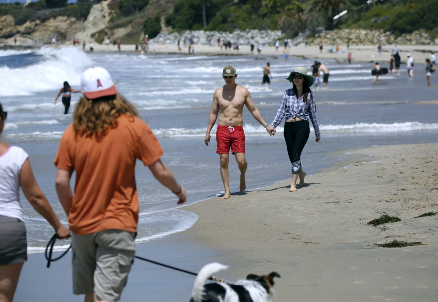 Dermatologists Dr. Anthony Huynh, center left, and Dr. Diana Zhang, both 47 and from Laguna Beach, enjoy a walk on the beach on a warm sunny day in Laguna Beach on Saturday.