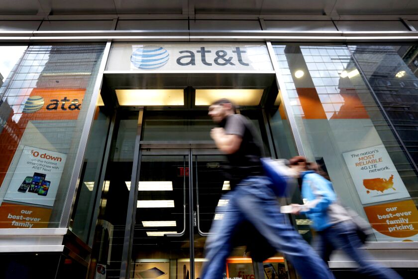 People pass an AT&T store along New York's Madison Avenue.