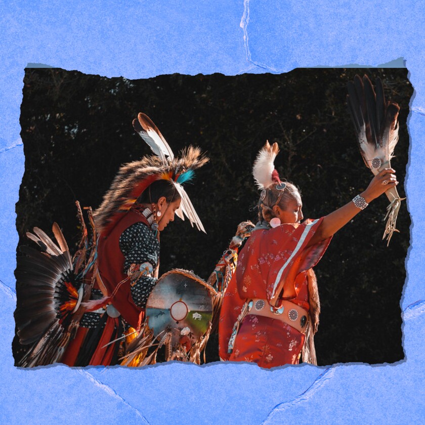 Two people in Native American costume are seen from the side.