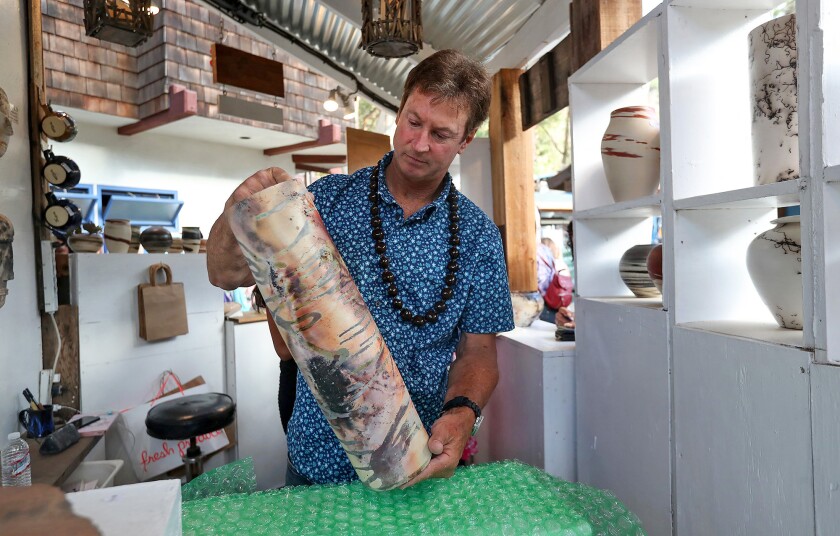 Ceramics exhibitor Robert Jones prepares to wrap a sold handmade pot during the 2022 Sawdust Festival preview night.