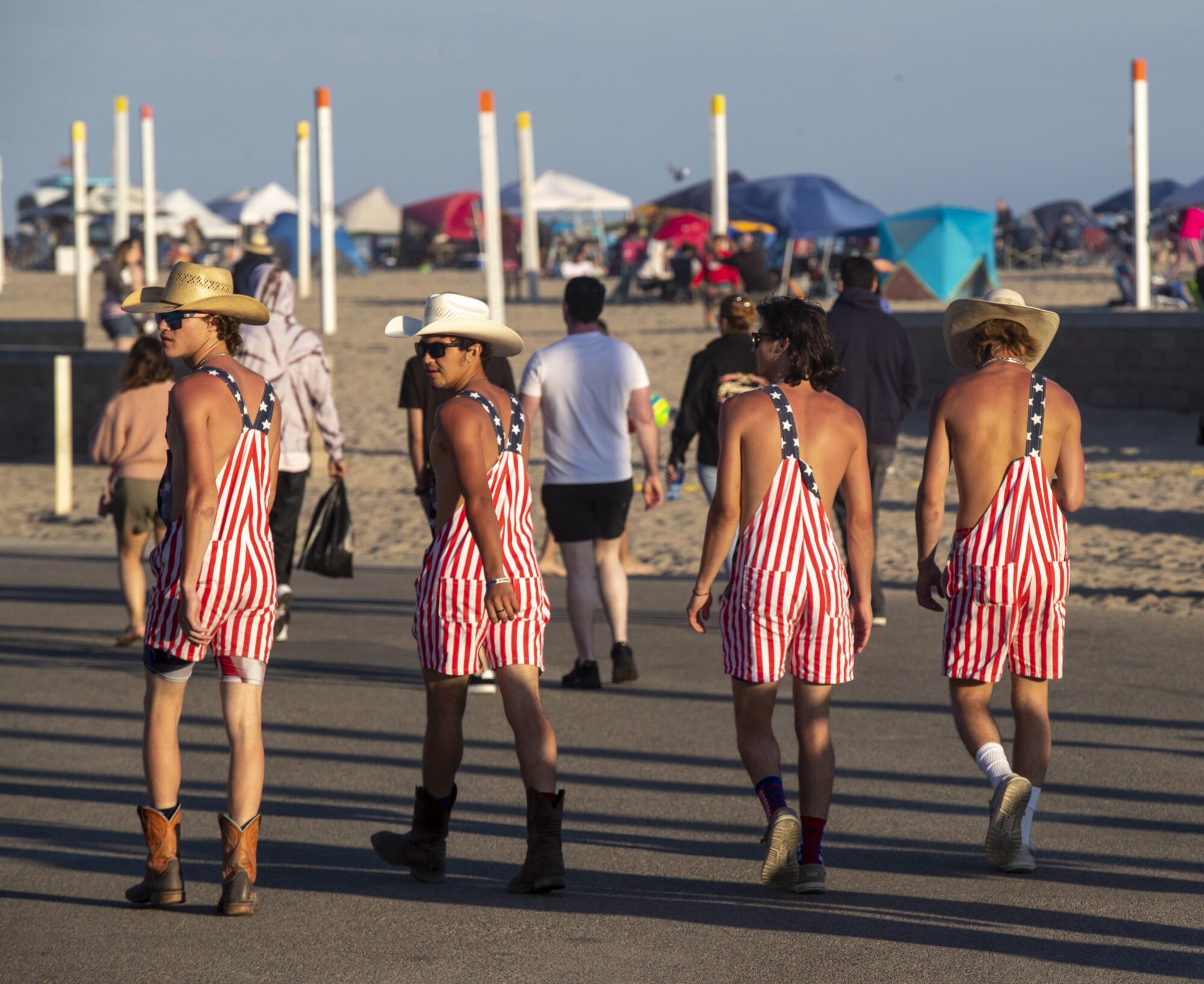 Four people wearing overalls in U.S. flag colors walk down a bike path 