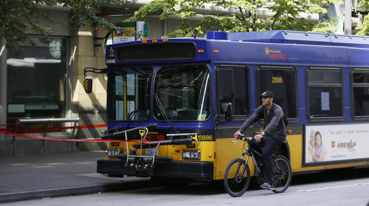 A cyclist rides past a bus in which the driver was shot by a gunman in downtown Seattle.