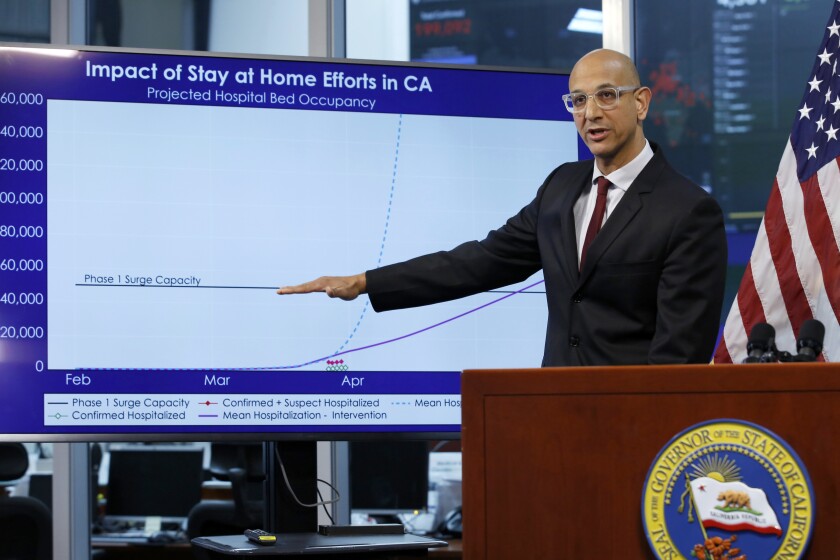 FILE - In this April 1, 2020, file photo Dr. Mark Ghaly, secretary of the California Health and Human Services, gestures to a chart showing the impact of the mandatory stay-at-home orders, during a news conference in Rancho Cordova, Calif. A technical problem has caused a lag in California's tally of coronavirus test results, casting doubt on the accuracy of recent data showing improvements in the infection rate and number of positive cases, and hindering efforts to track the spread, the state's top health official said Tuesday., Aug. 4. (AP Photo/Rich Pedroncelli, Pool, File)