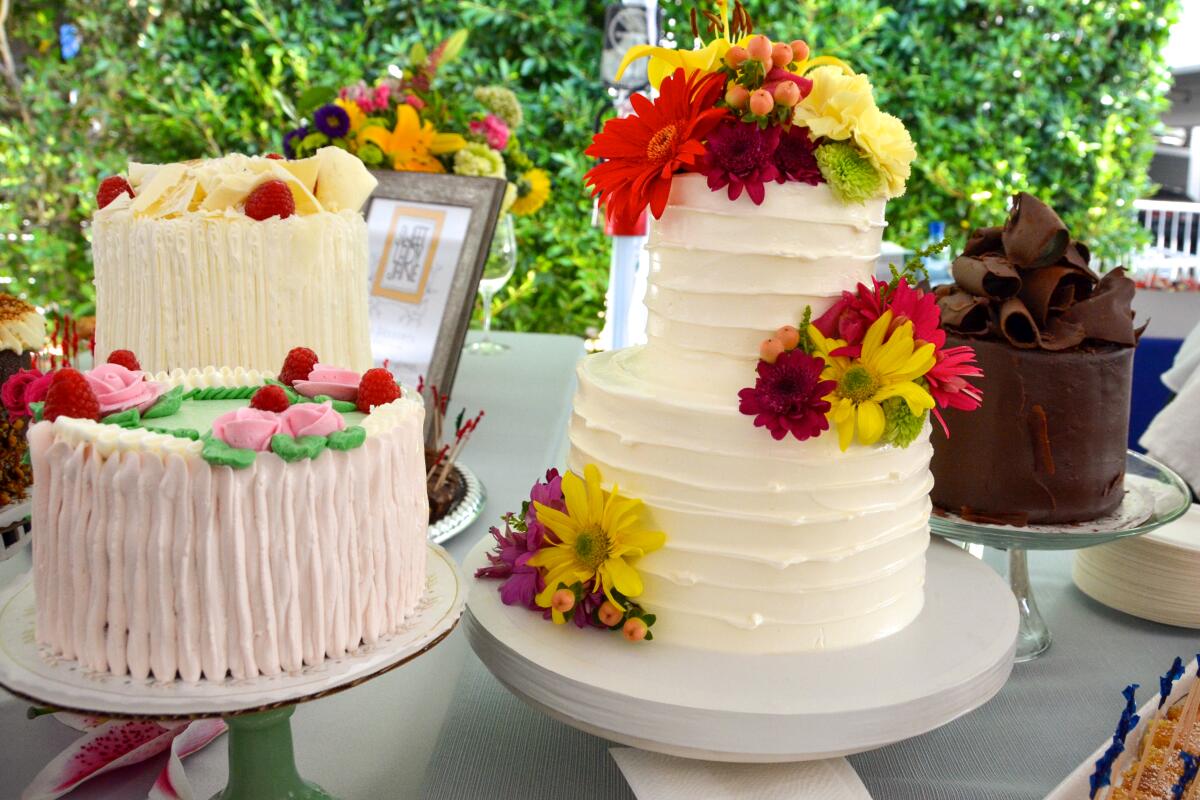 Two whole two-tiered cakes with white frosting and decorated with flowers