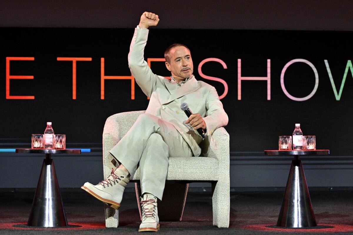 Robert Downey Jr. pumps a fist in the air while seated on stage.