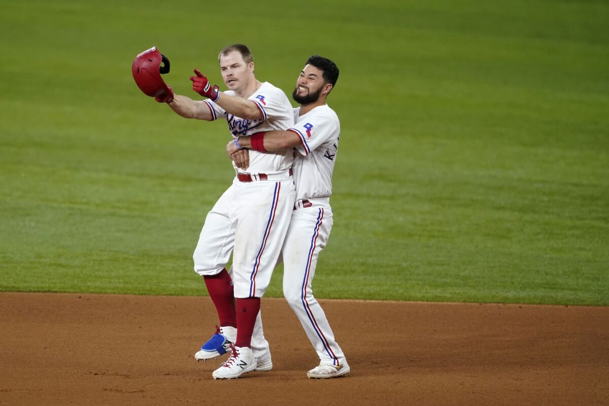 Texas Rangers' Brock Holt, left, and Isiah Kiner-Falefa, right, celebrate Holt's walk-off single in the 11th inning of the team's baseball game against the San Francisco Giants in Arlington, Texas, Wednesday, June 9, 2021. (AP Photo/Tony Gutierrez)