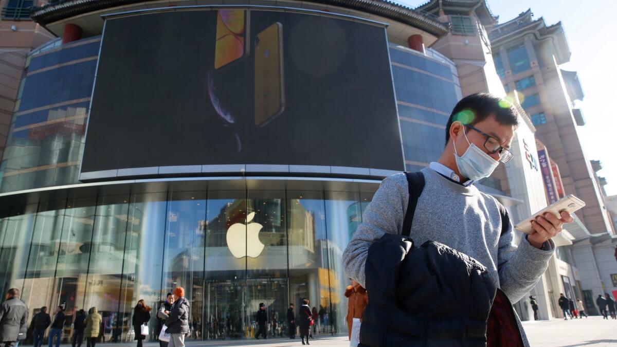 A man uses his smartphone outside an Apple store in Beijing.