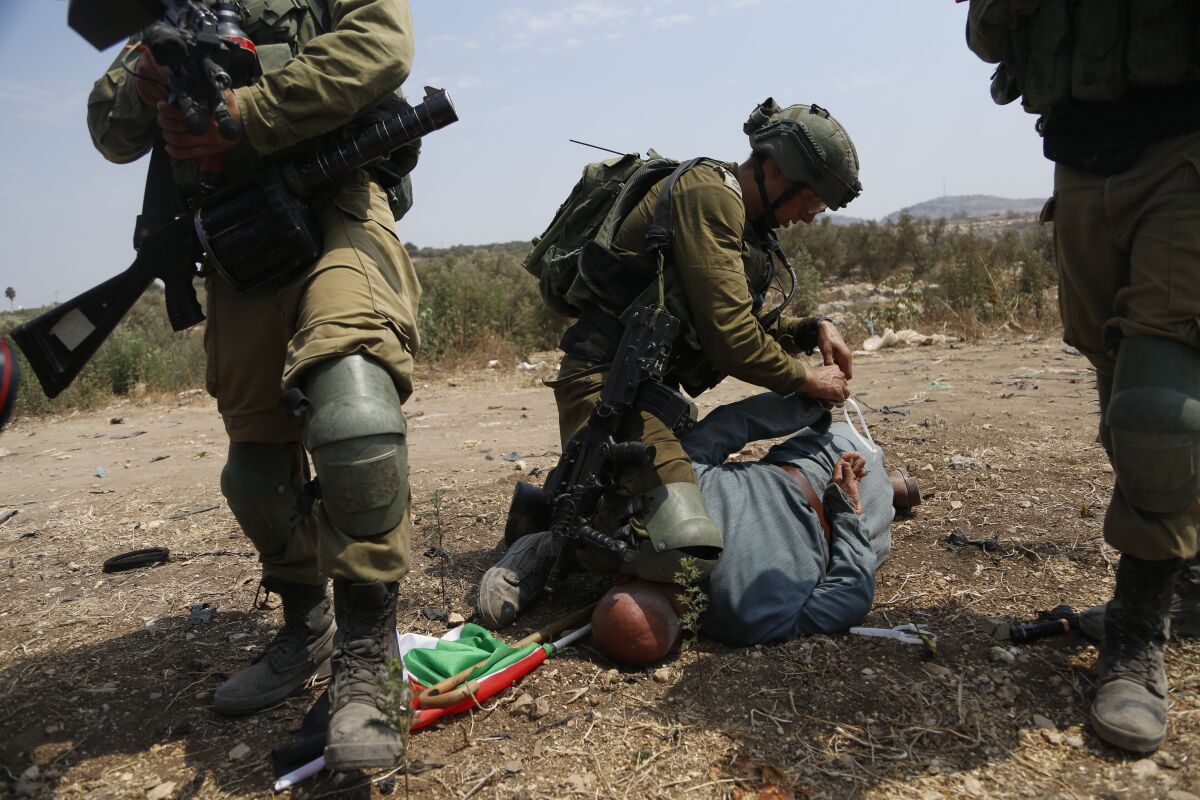 Israeli soldiers detain a Palestinian during a protest against expansion of Israeli settlements in the village of Shufa in the West Bank, Tuesday, Sep. 1, 2020.(AP Photo/Majdi Mohammed)
