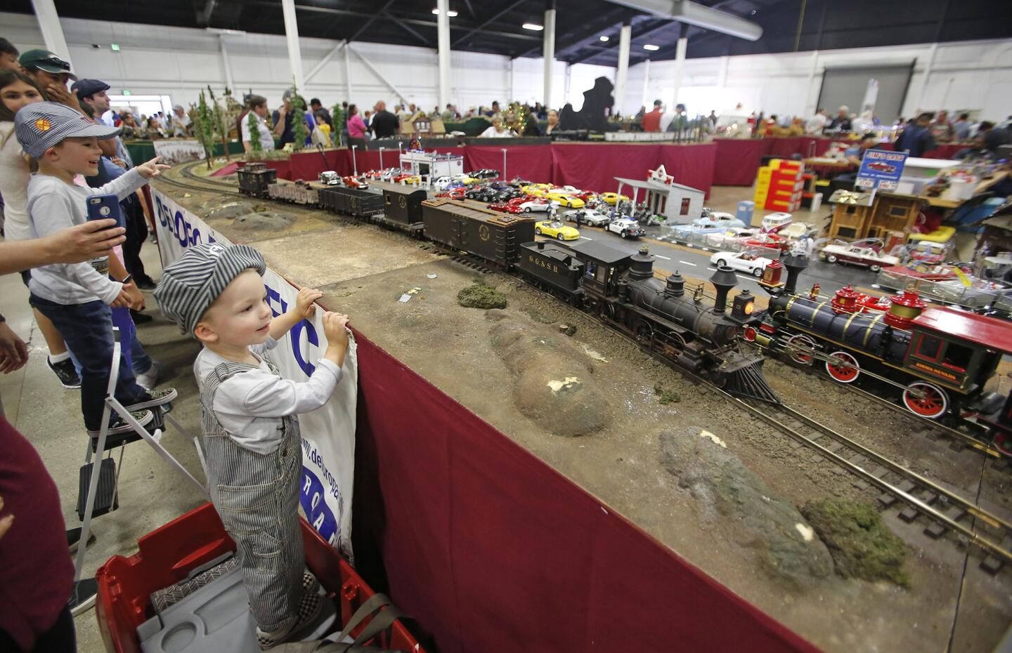 Ben Roberts, dressed in conductor gear, watches as two engines roll by compliments of the Del Oro Pacific large scale modular railroad display during the Great Train Show at the OC Fair and Events Center on Saturday.