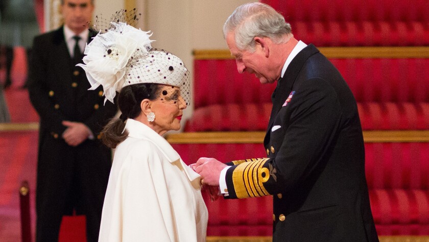 Actress Joan Collins receives the honor of damehood from Britain's Prince Charles, Prince of Wales, during an investiture ceremony at Buckingham Palace on March 26, 2015.