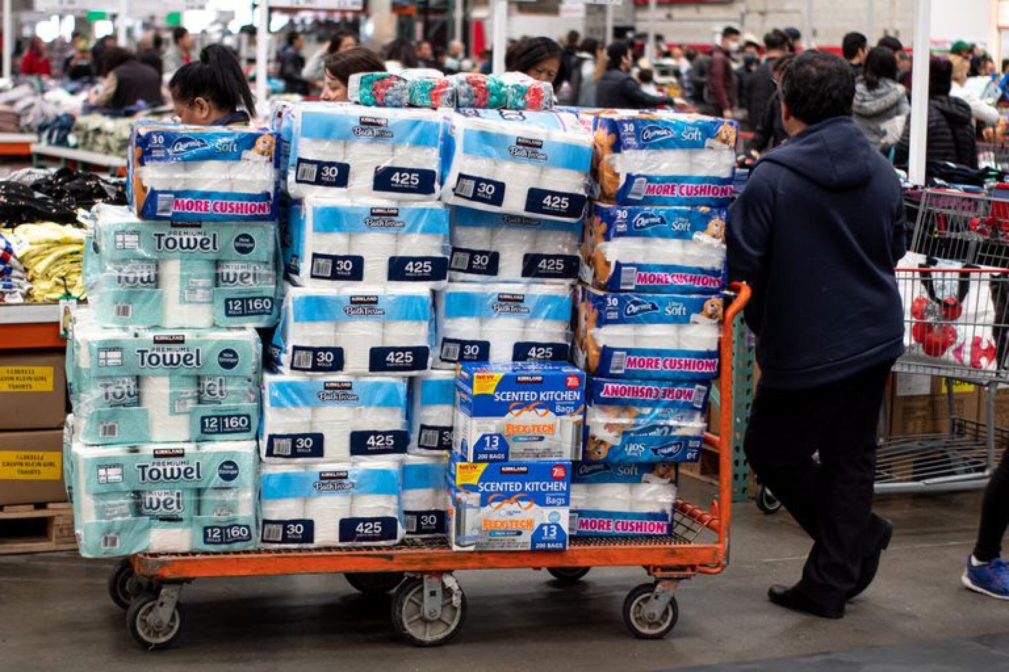 Stacks of paper towels, toilet paper and trash bags on a flatbed cart in Costco