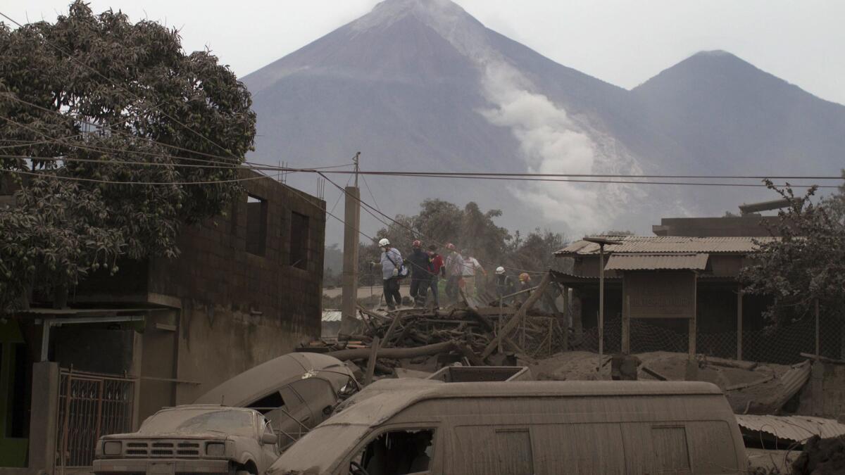 Rescue workers walk on rooftops blanketed with heavy ash in Escuintla, Guatemala, on Monday.