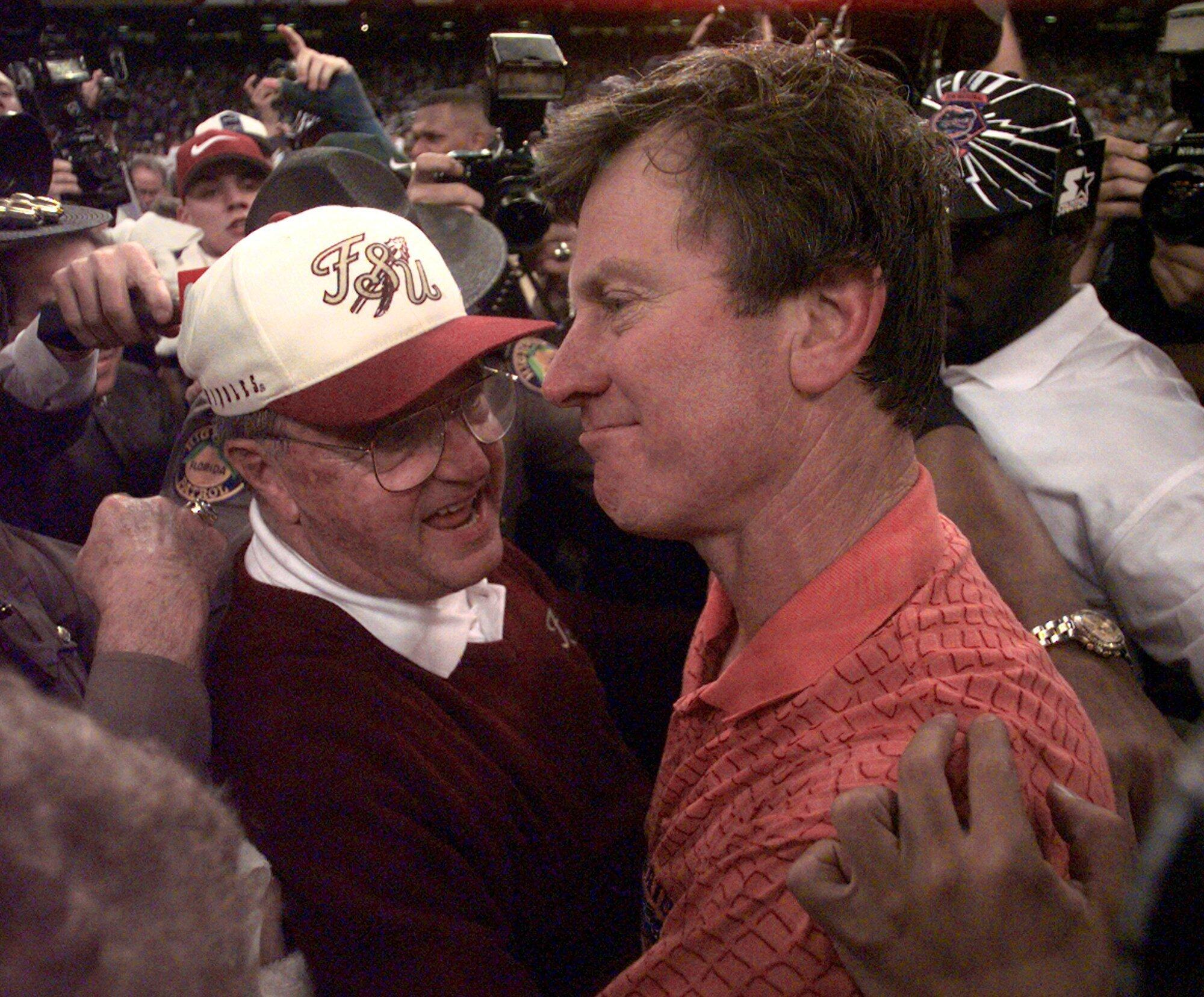 Amid a crush of people on the football field, Bobby Bowden speaks to Steve Spurrier. 