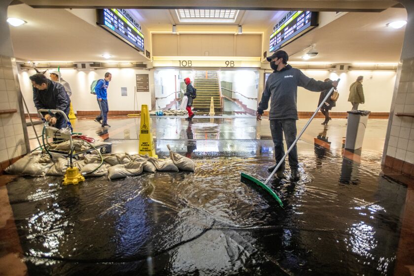 Los Angeles, CA - January 10: Gerardo Medina, 21, is cleaning up water inside Union Station on Tuesday, Jan. 10, 2023, in Los Angeles, CA. The torrential rain led to flooding in the pedestrian walkway inside Union Station. (Francine Orr / Los Angeles Times)