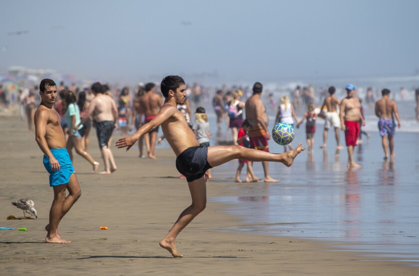 Beachgoers play at the water's edge in Huntington Beach last month.