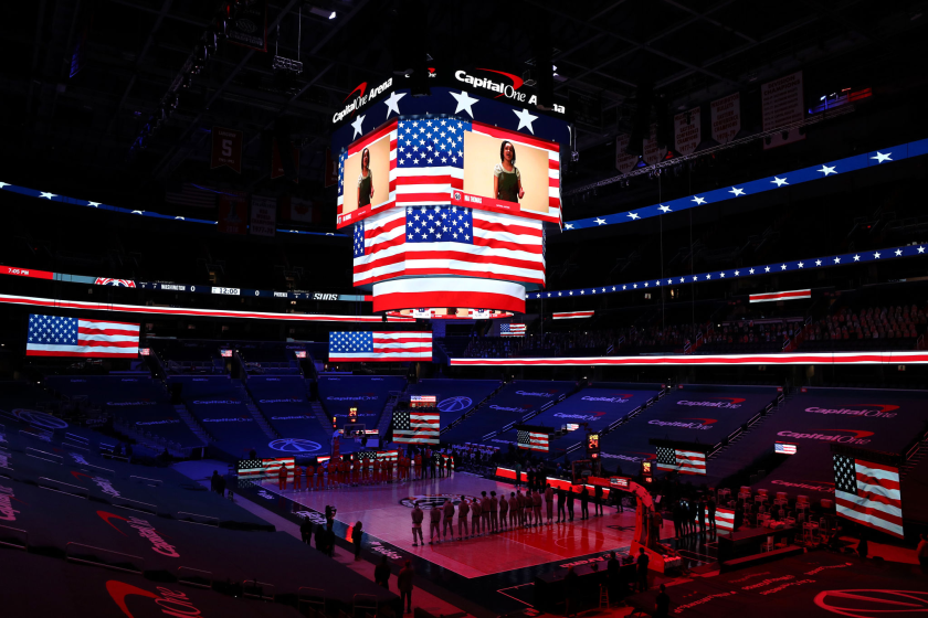 The Phoenix Suns and Washington Wizards stand in an otherwise empty arena during the playing of the national anthem.