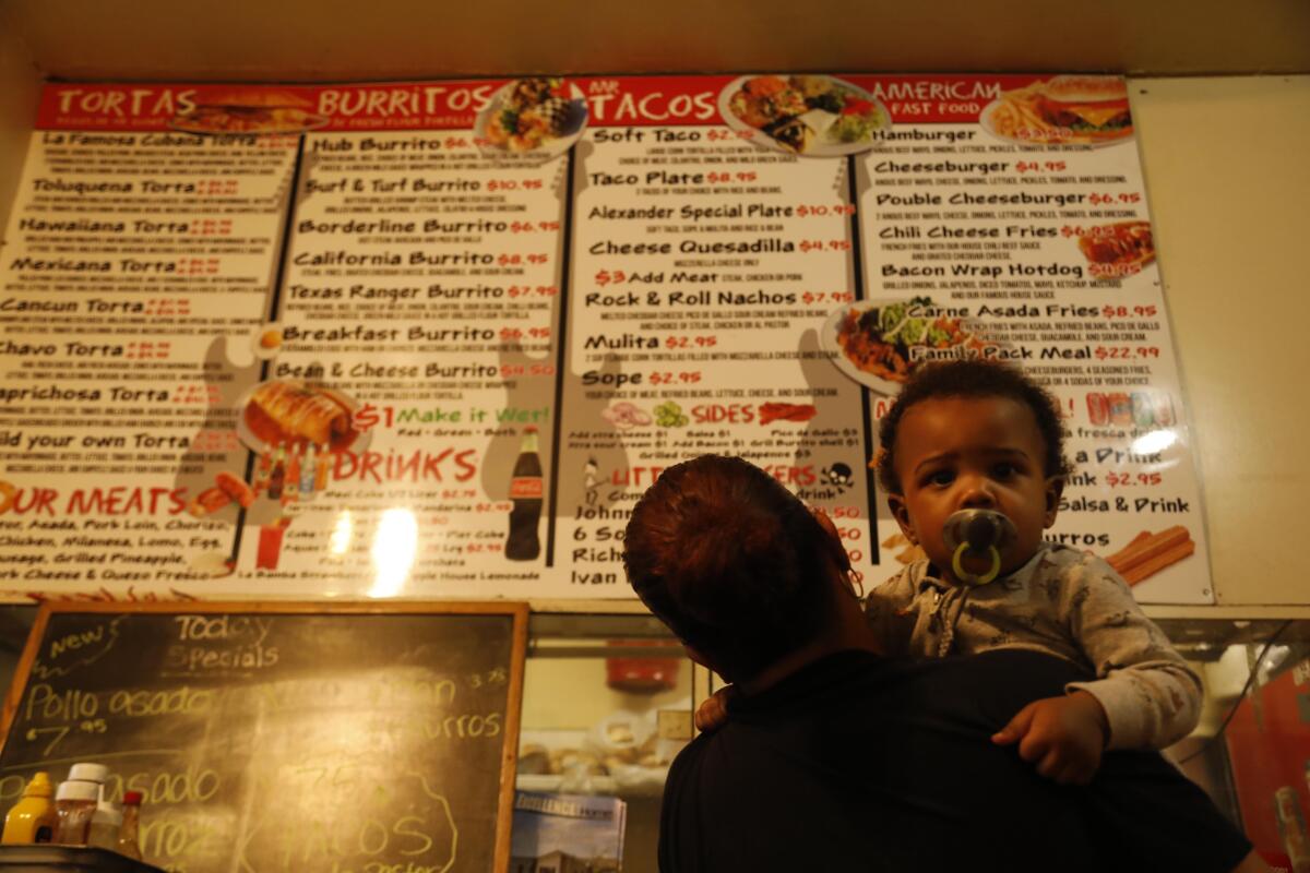 Yvelisse Cotto holds her 18-month-old grandson, Jase Carter, while trying to decide what to order.