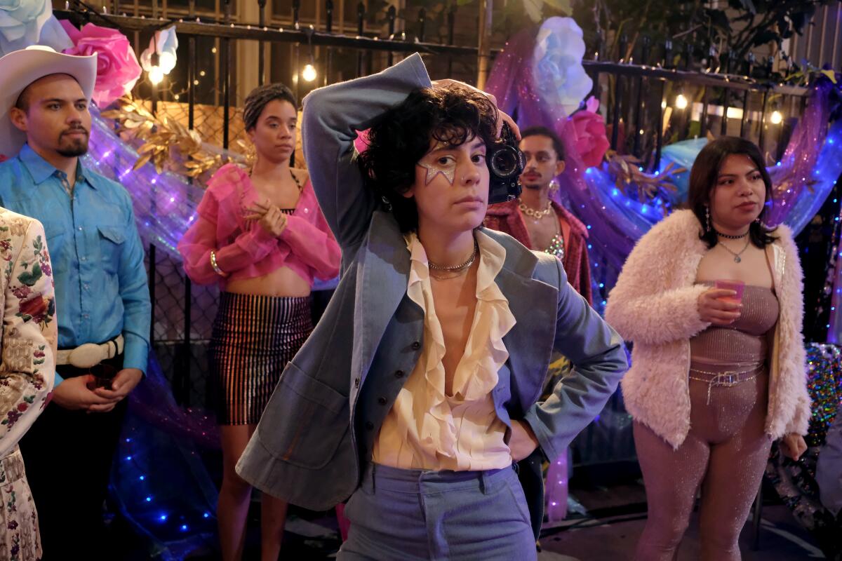 Actor Roberta Colindrez is shown in a blue suit in a party setting on the set of the TV show "Vida" 