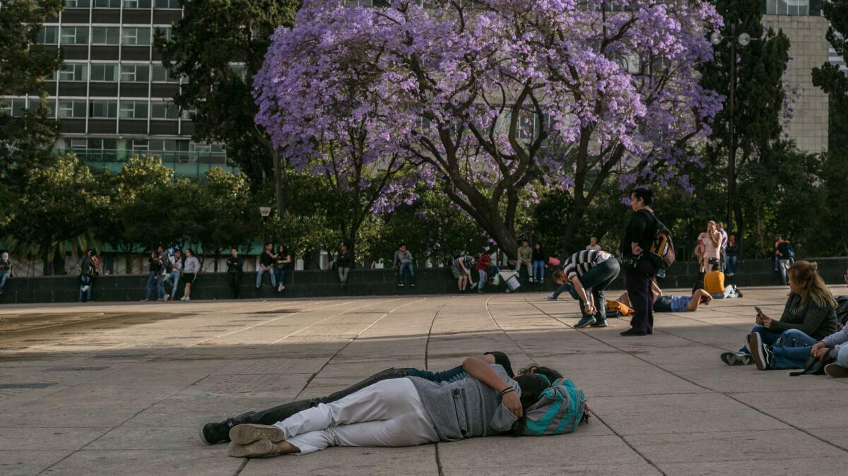 A couple rests in an embrace in front of the Revolution monument in Mexico City.