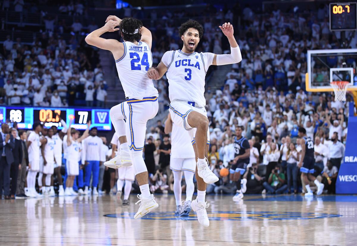 UCLA's Jaime Jaquez Jr. and Johnny Juzang jump and raise their hands on court.