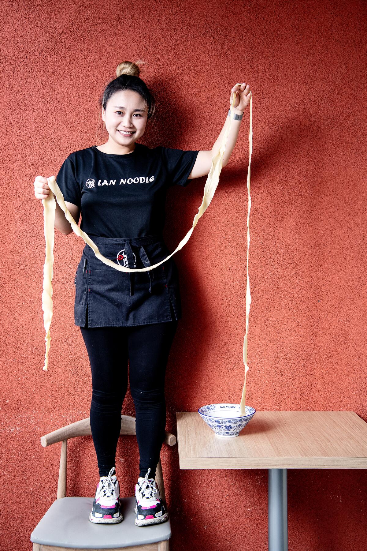 Portrait of owner Esther Yuan showcasing the length of the longevity noodle at LAN Noodle in West Covina.