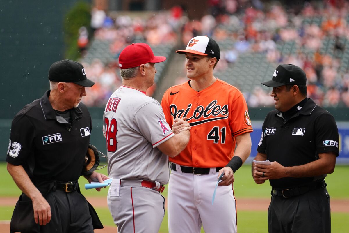 Los Angeles Angels interim manager Phil Nevin, center left, and his son, Baltimore Orioles third baseman Tyler Nevin, center right, shake hands after delivering their team's lineup cards as home plate umpire Lance Barksdale, left, and second base umpire Nestor Ceja look on prior to a baseball game, Saturday, July 9, 2022, in Baltimore. (AP Photo/Julio Cortez)