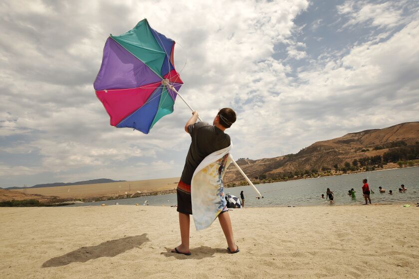 CASTAIC, CA - JULY 08: Zachary Pruett, 10, catches wind with this umbrella as he was putting it away after he and his Mom Amanda Pruett, from Santa Clarita finish their morning at Castaic Lake Lagoon. The pair came to "Cool off before the sun becomes dangerous." Said Amanda. Temperatures began to soar Thursday morning as a new heatwave is predicted to bring dangerously hot weather to California's inland regions this week, with relentlessly high temperatures that continue to torment the west coast. Castaic Lake Lagoon is now open daily 10am to 6pm. Castaic Lake Lagoon on Thursday, July 8, 2021 in Castaic, CA. (Al Seib / Los Angeles Times).