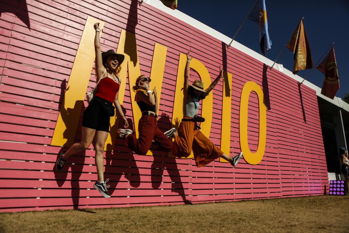 Los Angeles natives Audrey Whitby, left, Sabine Routtene and Victoria Moroles jump in front of the Indio sign.