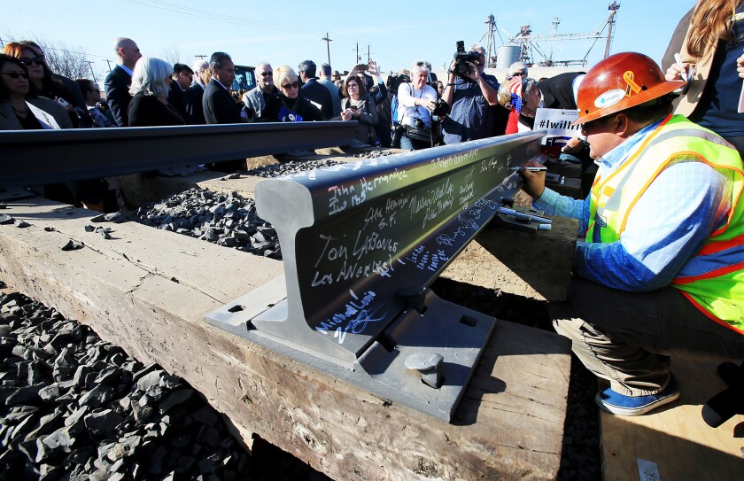 Invited guests sign segments of railroad track during a groundbreaking ceremony for a bullet train station in Fresno on Jan. 6.