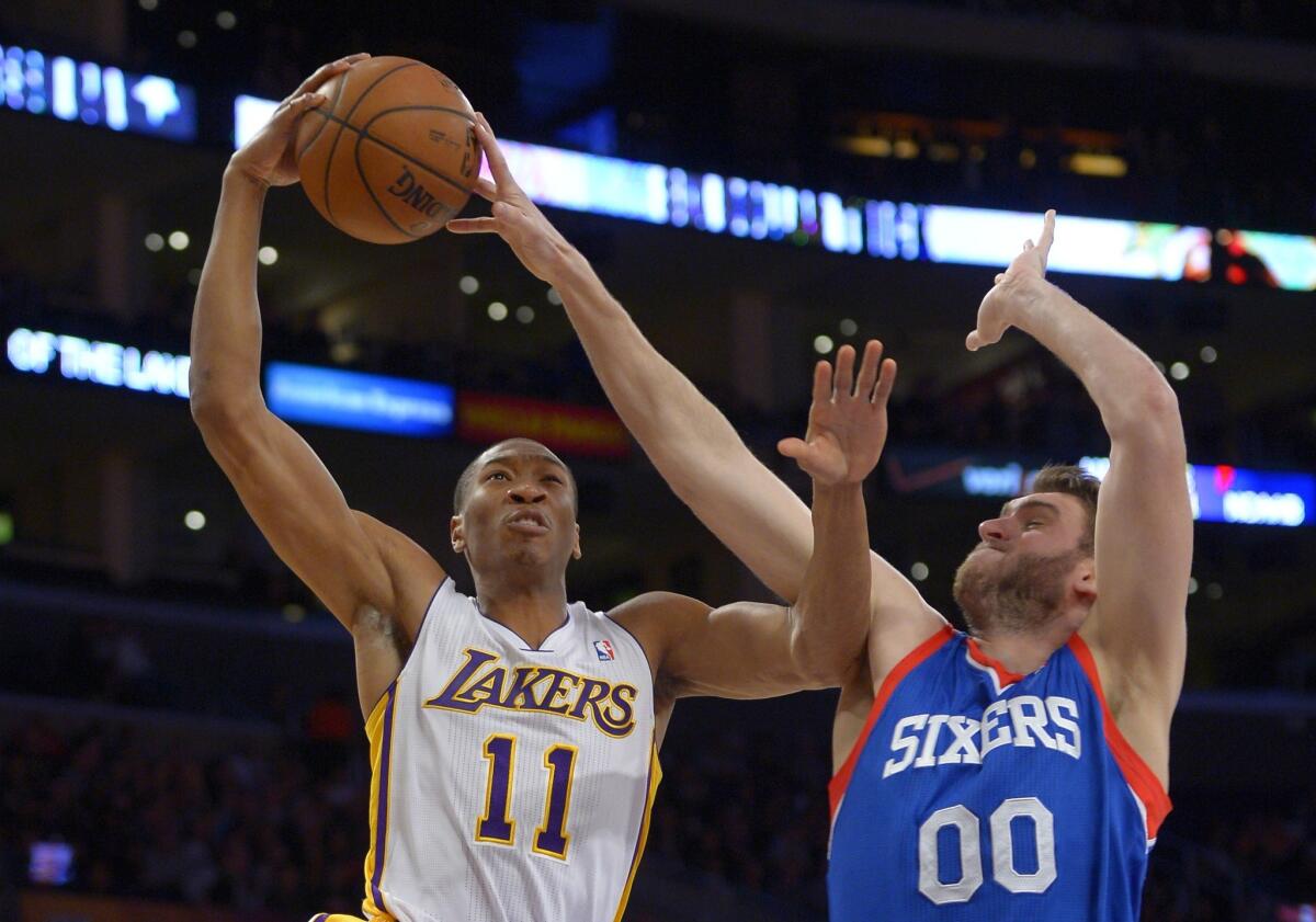 Philadelphia 76ers center Spencer Hawes, right, blocks a shot by Lakers guard Wesley Johnson during the first half of a game at Staples Center.