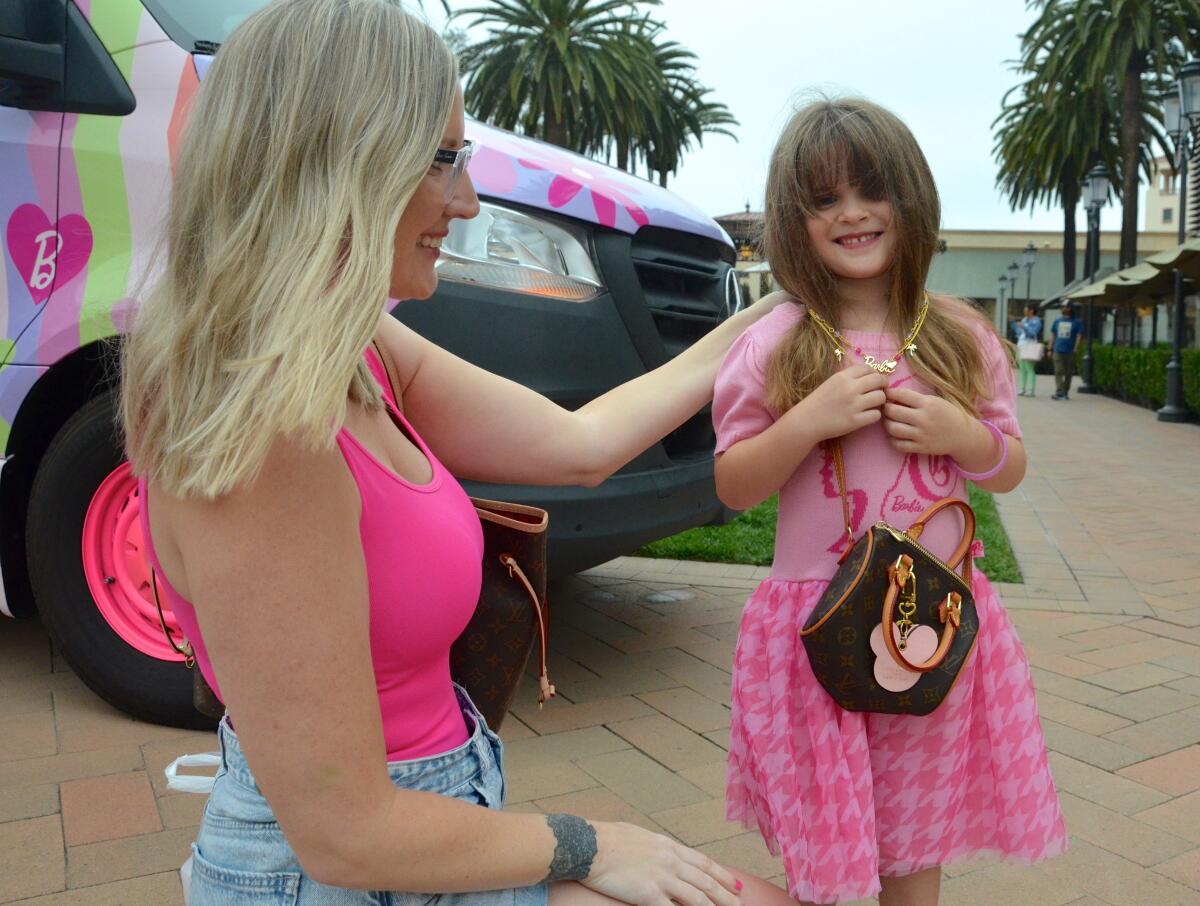 Lindsay Allen lets daughter Everly try on a Barbie necklace from the Barbie truck.