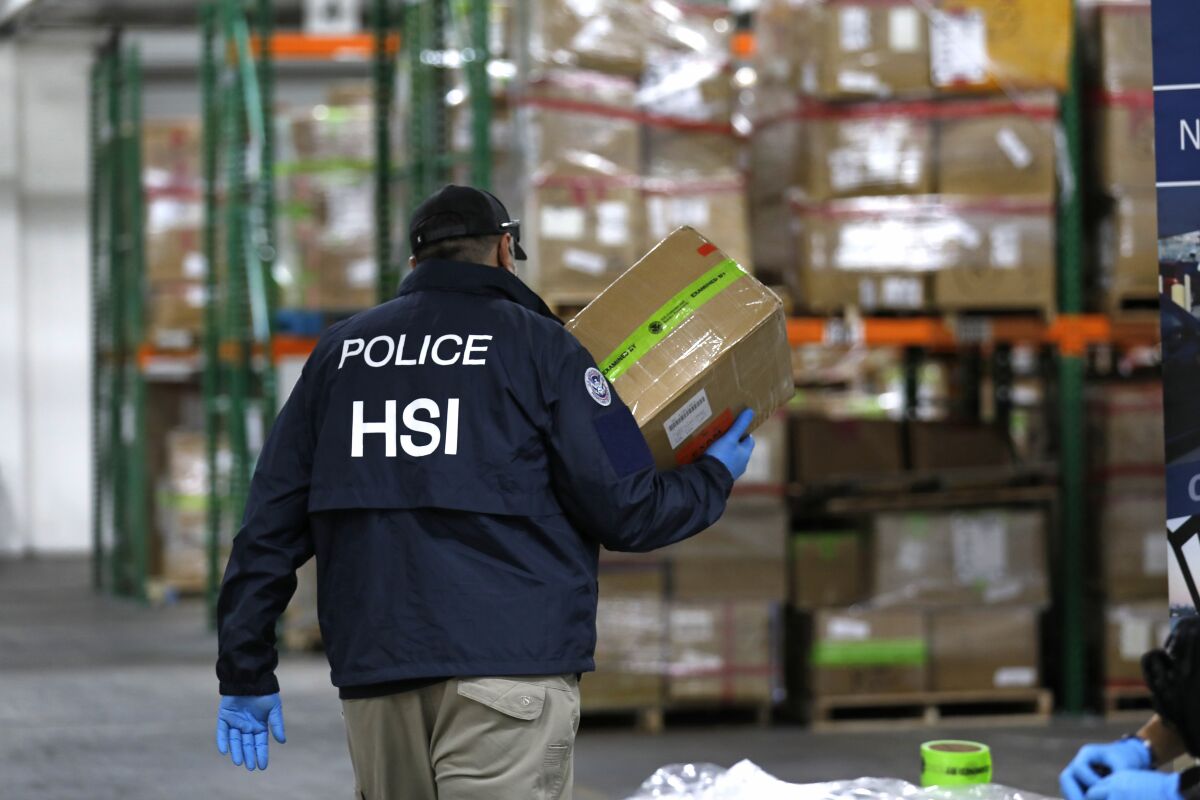 A Homeland Security Investigations officer carries a box of counterfeit goods at the Air Freight Federal Inspection Facility