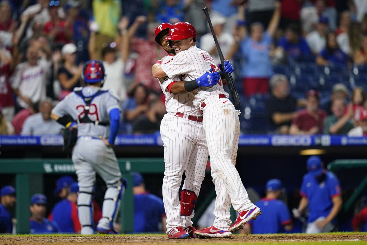 Philadelphia Phillies' Andrew Knapp, right, and Jean Segura celebrate after Knapp scored the game-winning run on a passed ball during the ninth inning of a baseball game against the Chicago Cubs, Wednesday, Sept. 15, 2021, in Philadelphia. (AP Photo/Matt Slocum)