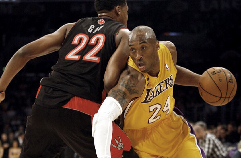 Lakers guard Kobe Bryant spins past Raptors forwrd Rudy Gay on a drive to the basket in the first half Friday night at Staples Center.