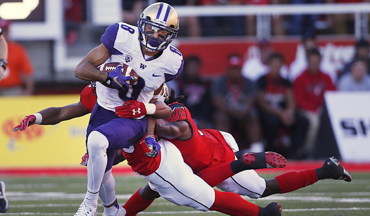 Washington's Dante Pettis (8) runs out of the tackles of Utah's Armand Shyne (23) and Tim Patrick (12) to score the winning touchdown during the second half Saturday.